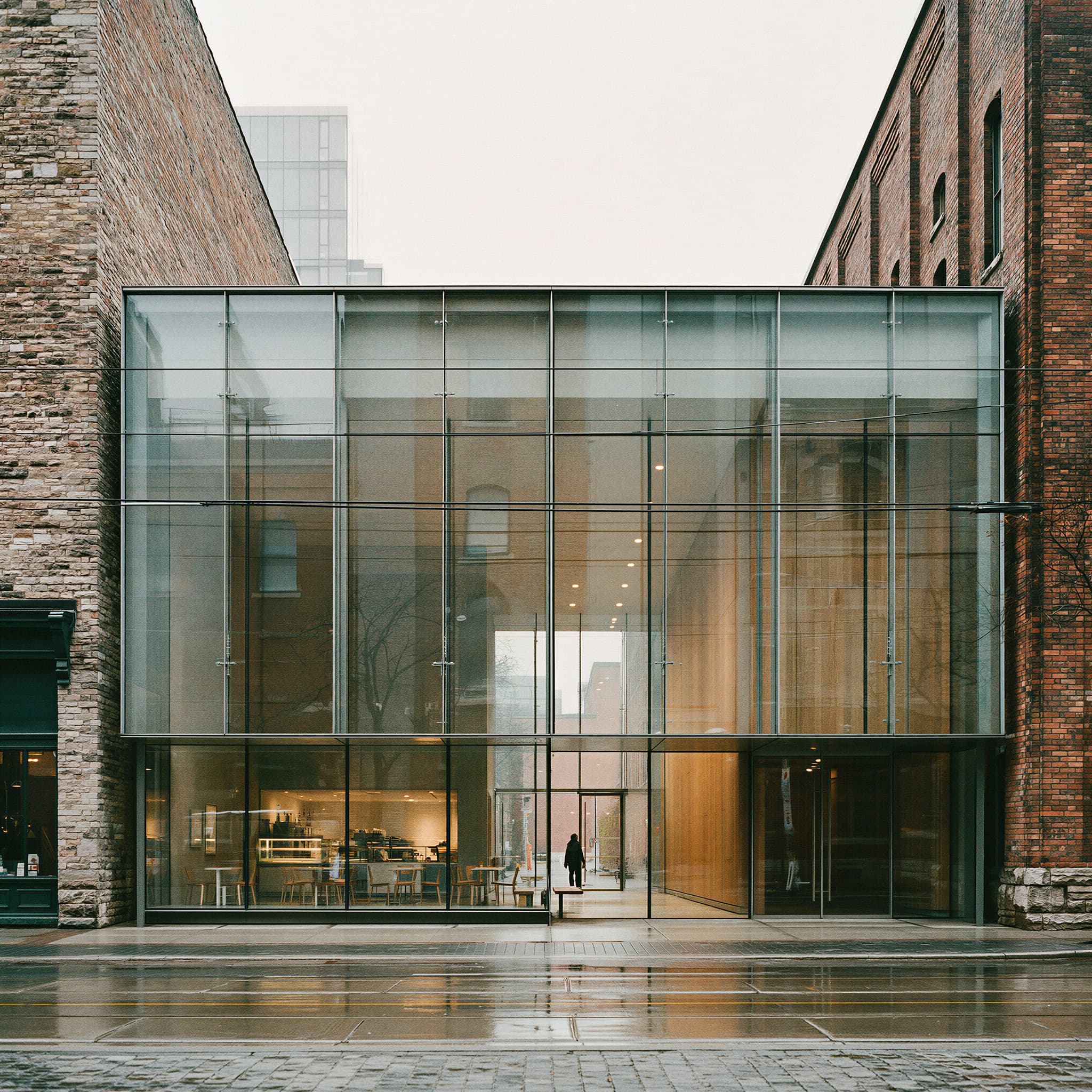 Urban infill architectural photography showing glass and steel building woven into historic brick warehouse facade, created with Midjourney, stamped with VISID structured metadata