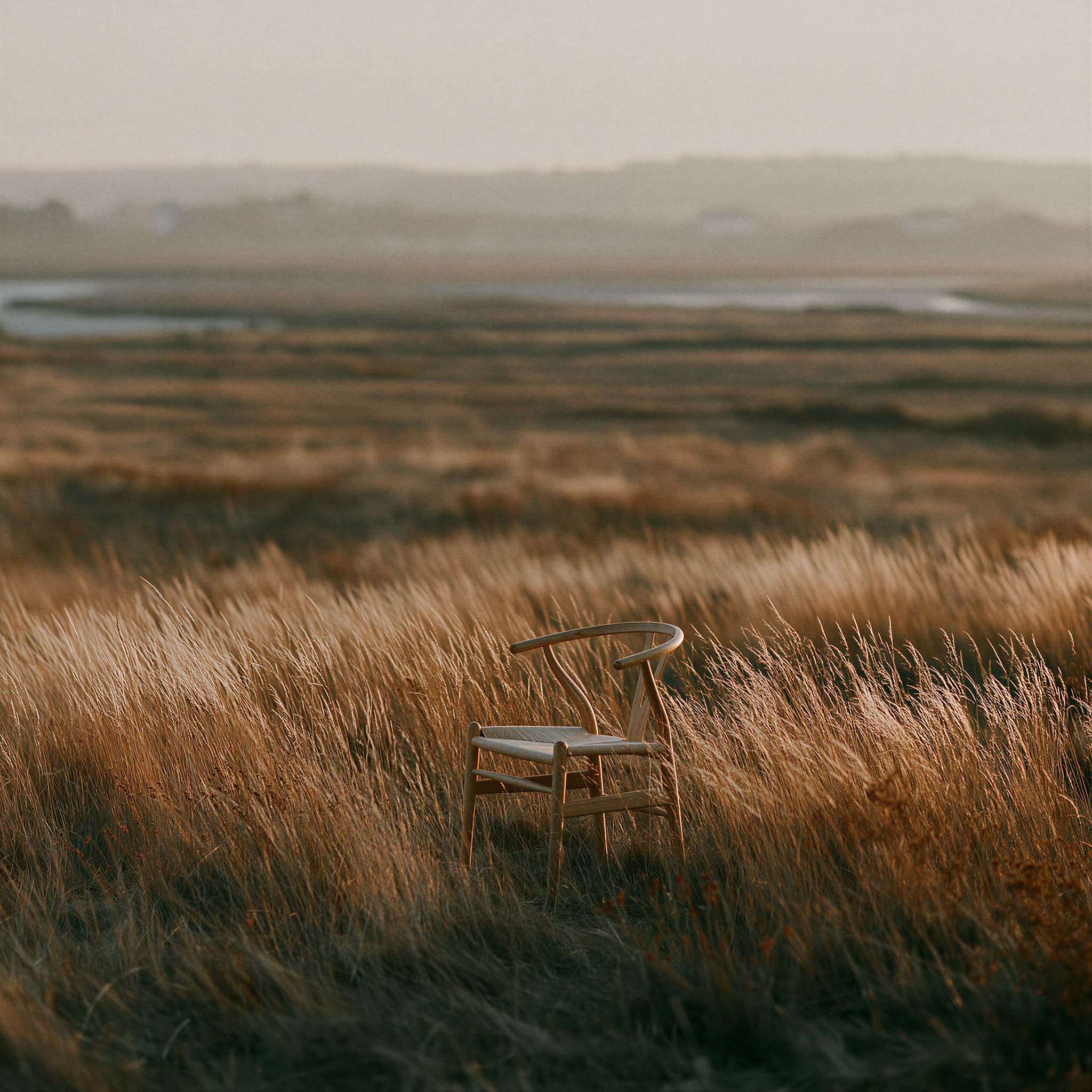 Hans Wegner Wishbone Chair in a sunlit grassy field, simulated product photography created with Midjourney, stamped with VISID structured metadata
